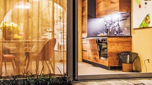 A modern kitchen with wooden cabinetry, a built-in oven, and a large window overlooking a dining area. - Garden Suite by Interhome (Ronco sopra Ascona)