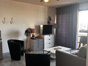 Una sala de estar con televisor, ventilador, lámpara y sofá.