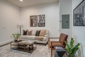 Ein modernes Wohnzimmer mit einer Couch, einem Couchtisch, einem Sessel und gerahmten Kunstwerken an der Wand.