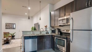 A modern kitchen with stainless steel appliances, dark cabinetry, and a dishwasher. - Lofts at 30th-Urban Nest-4 Mins to Broadway! (Nashville)