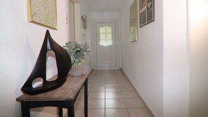 A hallway with a wooden bench, a vase with plants, and framed pictures on the walls. - Beautiful apartment with a view of the vineyards/on the banks of the Moselle/2 terraces just for you (Bruttig-Fankel)