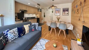 A modern apartment with a living room, dining area, and kitchen. - Luxurious Mountain Apartment, 2 Beds, Terrace + High-End Amenities, Close to Village & Ski Bus (Samoëns)