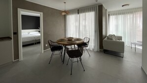 A modern hotel room with a dining area, a sofa, and a bed. - Apartamentos Las Indianas (Llanes)