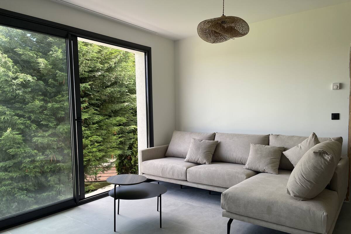 A modern living room with a large window, a sofa, and a coffee table.