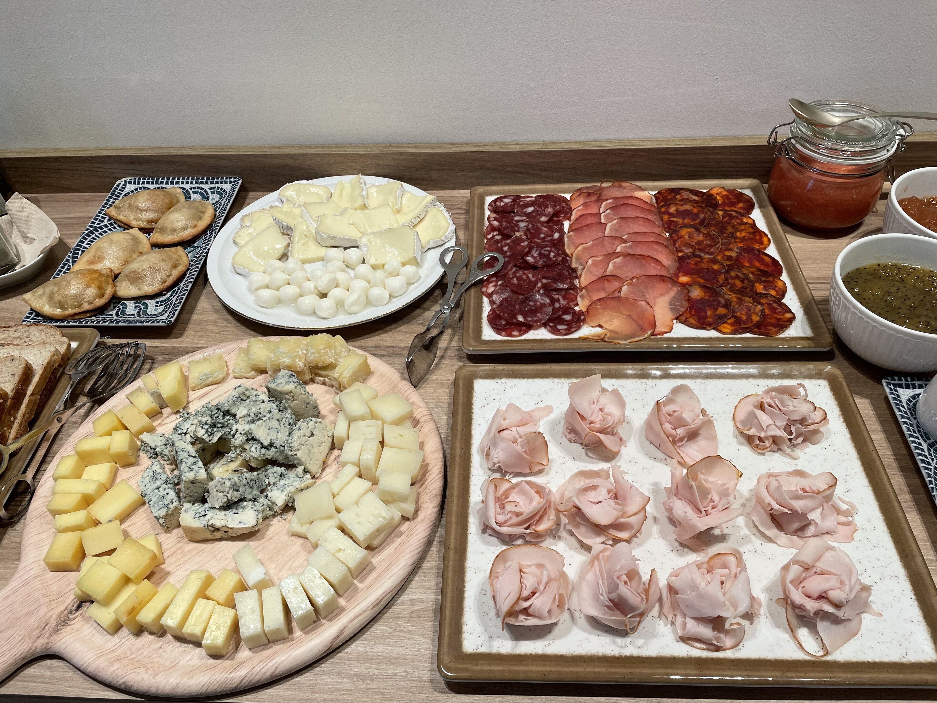 Eine Auswahl an Käse, Fleischwaren und Gebäck auf einem Holztisch.
