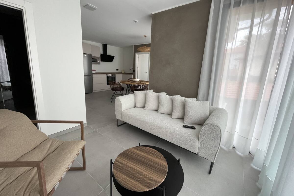 A modern living room with a sofa, a round wooden table, and a chair.