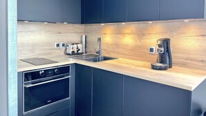 A modern kitchen with dark cabinetry, a wooden countertop, a built-in oven, a toaster, a sink, and a coffee maker. - Duplex, 45 m2, sleeps 8 - Duplex 45 m2, 8 couchages, vue imprenable (Alpe d'Huez)