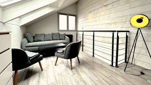 A modern loft bedroom with a sloped ceiling, a grey sofa, two armchairs, a small table, and a floor lamp. - Duplex, 45 m2, sleeps 8 - Duplex 45 m2, 8 couchages, vue imprenable (Alpe d'Huez)
