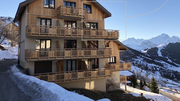A multi-story wooden chalet with balconies, set against a snowy mountain backdrop. - Duplex, 45 m2, sleeps 8 - Duplex 45 m2, 8 couchages, vue imprenable (Alpe d'Huez)