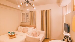 A hotel room with a bed, a desk, a TV, and a ceiling light fixture.