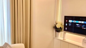 A modern living room with a sofa, a TV mounted on a wall, and a decorative vase with flowers.