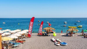 A beach with umbrellas, lounge chairs, and a clear blue sky.