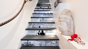 A staircase with comic strip illustrations on the steps and a bust sculpture on the right. - Exceptional modern apartment with majestic sea view in Letojanni - DiCasaInSicilia (Letojanni)