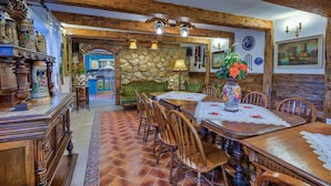 A dining area with wooden furniture, a stone wall, and a green sofa. - Luxury Chalet with private swimmingpool located in residential Saxon area (Cristian)