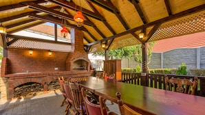 An outdoor patio with a brick fireplace, wooden table, and chairs. - Luxury Chalet with private swimmingpool located in residential Saxon area (Cristian)