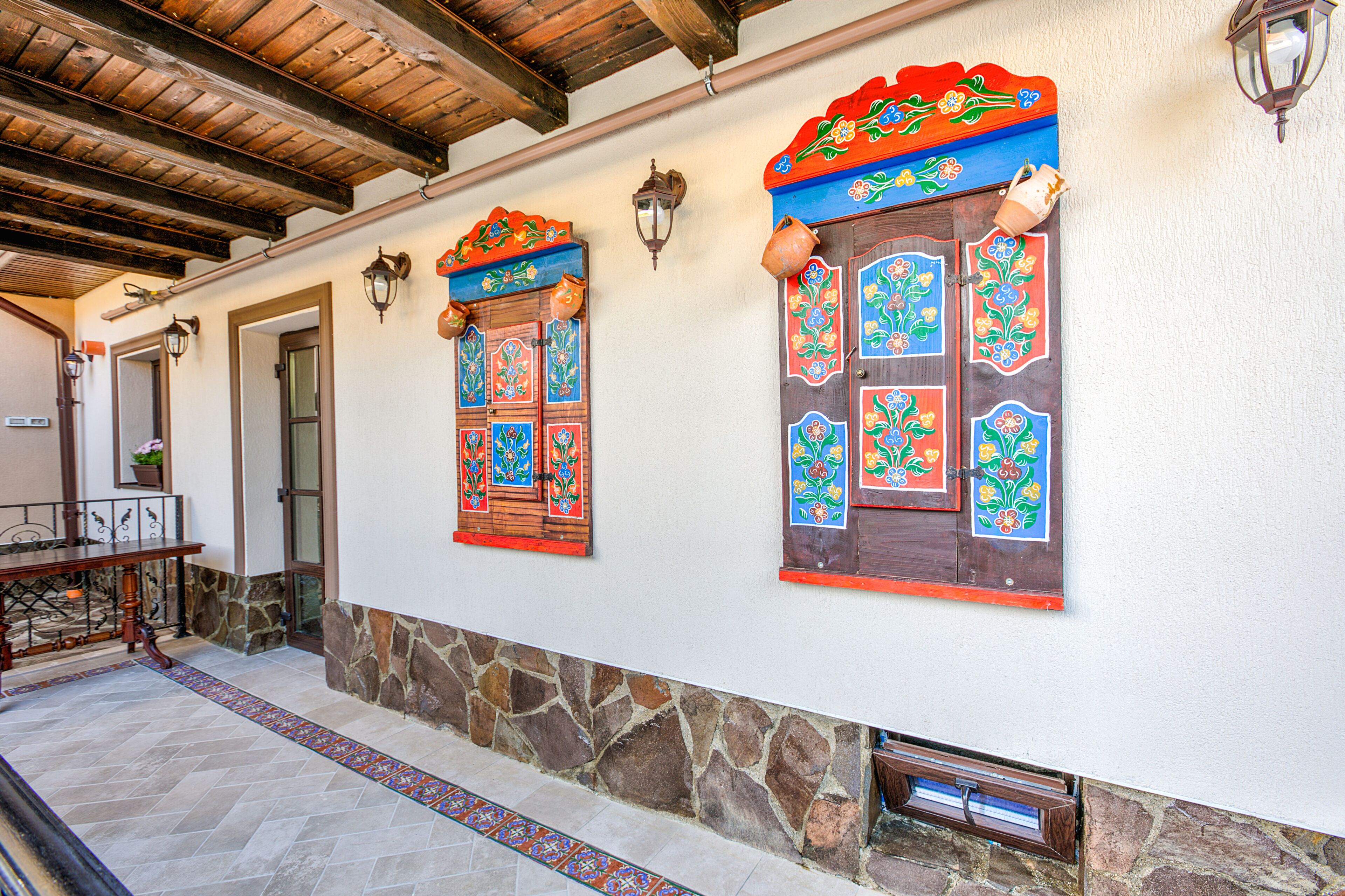 A building with decorative wooden doors and windows, stone walls, and a tiled floor.