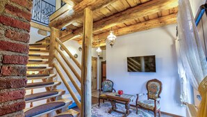 A wooden staircase with a brick wall, a wooden table with chairs, and a patterned rug. - Luxury Chalet with private swimmingpool located in residential Saxon area (Cristian)