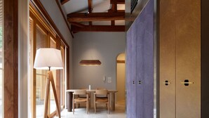 Een modern interieur met zichtbare houten balken, een plafondventilator, een eetgedeelte met tafel en stoelen, en een grote kledingkast.