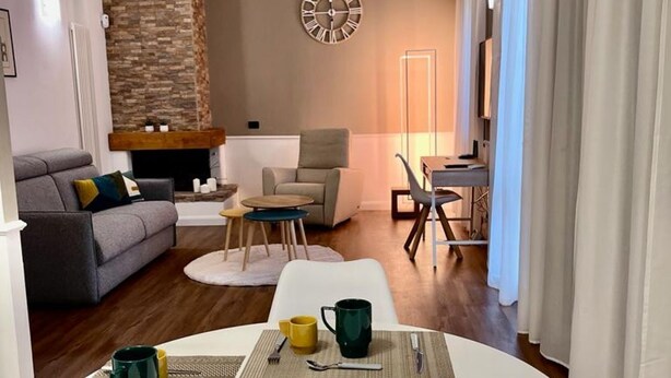 A living room with a sofa, armchair, dining table, and a fireplace. - GuestHost - Bright and welcoming 70sqm apartment with garden equipped with table and chairs, located on the ground floor of a period building that can accommodate up to 5 people! The apartment is located a few steps from the center of Vicenza. Convenient (Vicenza)
