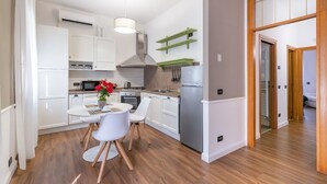 A modern kitchen with white cabinets, a stainless steel range hood, and a dining area with a white table and chairs. - GuestHost - Bright and welcoming 70sqm apartment with garden equipped with table and chairs, located on the ground floor of a period building that can accommodate up to 5 people! The apartment is located a few steps from the center of Vicenza. Convenient (Vicenza)