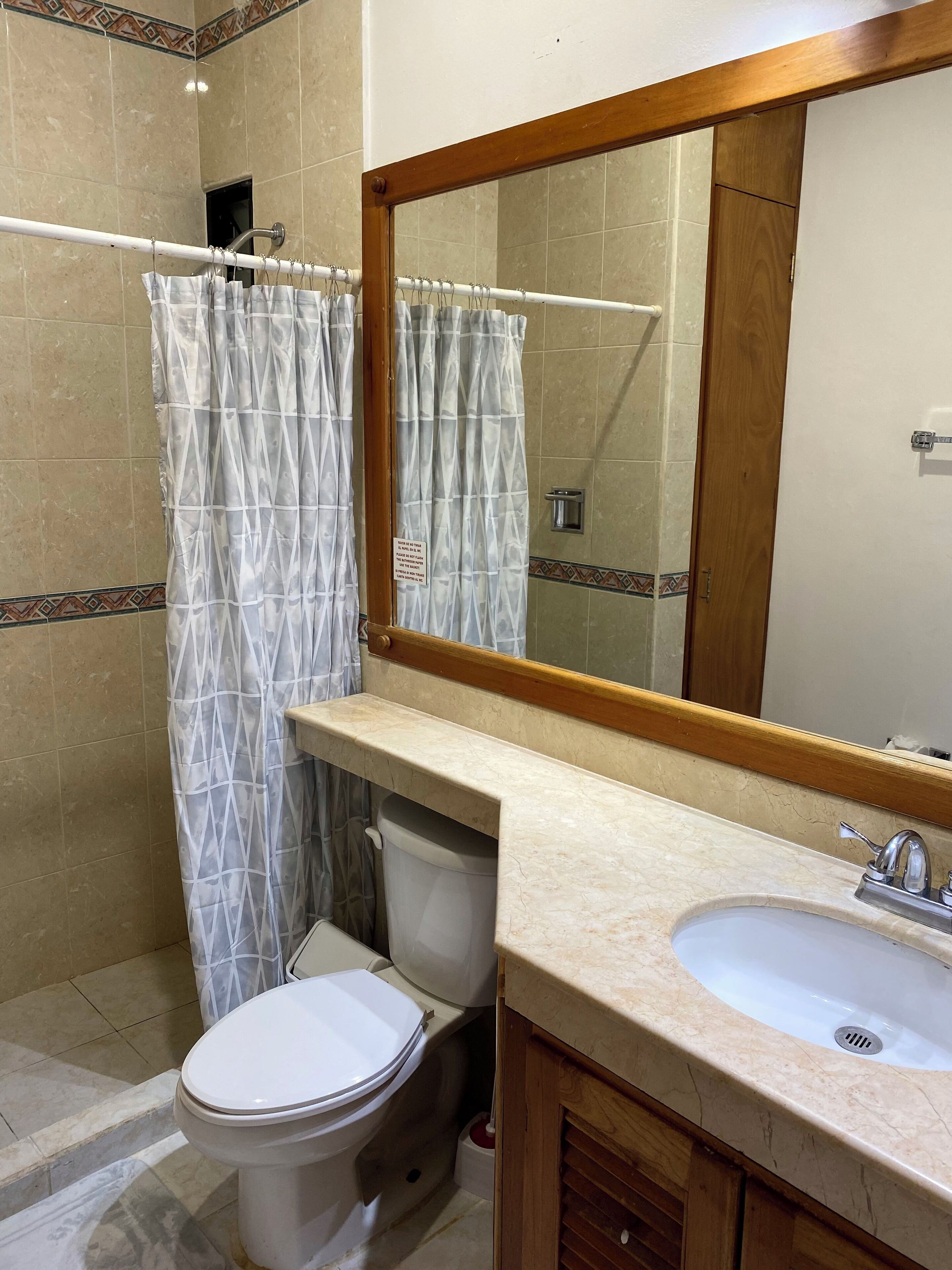 Une salle de bain avec des toilettes, un lavabo et un rideau de douche.