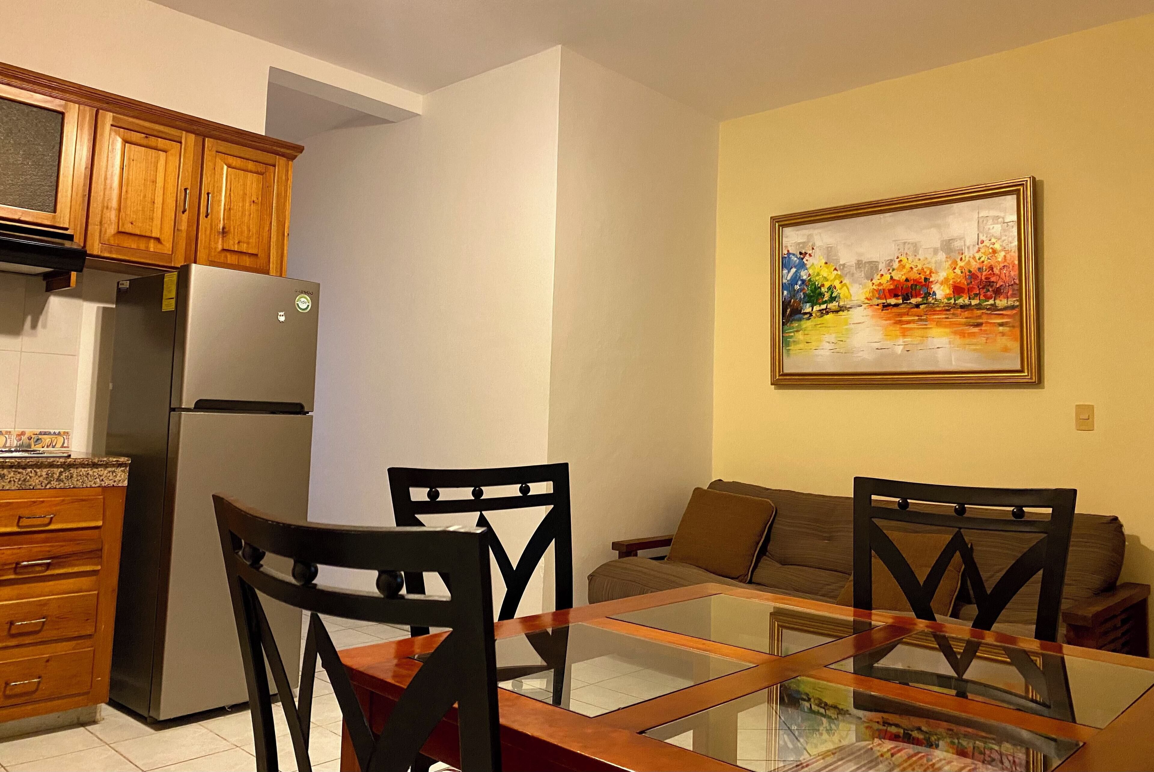 Una cocina moderna con armarios de madera, un refrigerador de acero inoxidable y una mesa de comedor de vidrio con sillas.