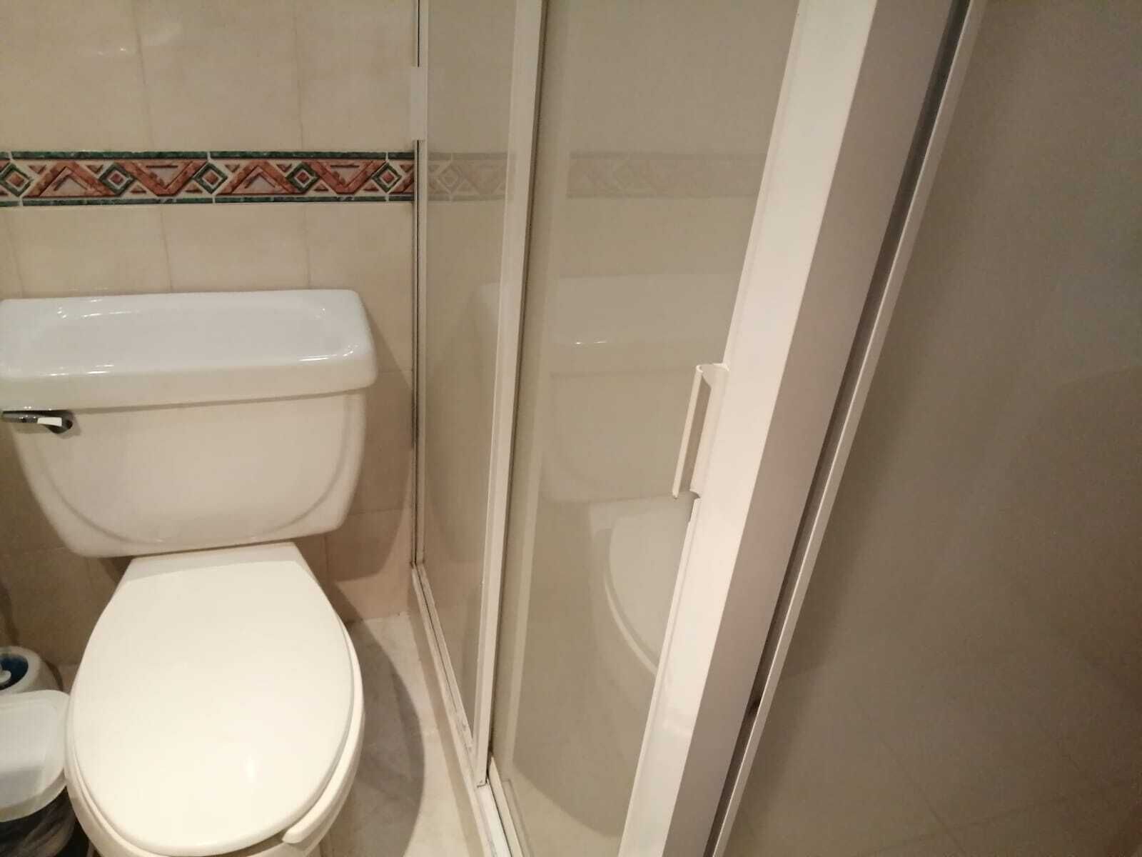 Un bagno con il water, cabina doccia e zoccolo piastrellato.
