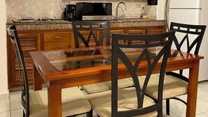 A kitchen with wooden cabinets, a microwave, a refrigerator, and a dining table with chairs. - Quinta Sea (Playa del Carmen)