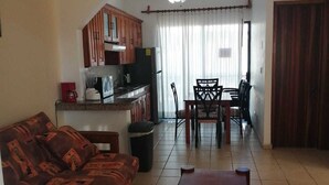 A living room with a sofa, a coffee table, and a dining area with chairs and a table. - Quinta Sea (Playa del Carmen)