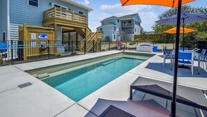 A swimming pool with a wooden deck, lounge chairs, and umbrellas. - Your Fresh Beach Oasis! (Corolla)