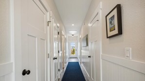 A hallway with white doors, a blue carpet, and a framed picture on the wall. - Your Fresh Beach Oasis! (Corolla)