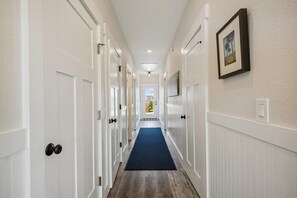 A hallway with white doors, a blue carpet, and a framed picture on the wall.