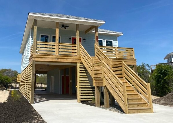 A two-story building with a wooden deck and stairs leading to a balcony.