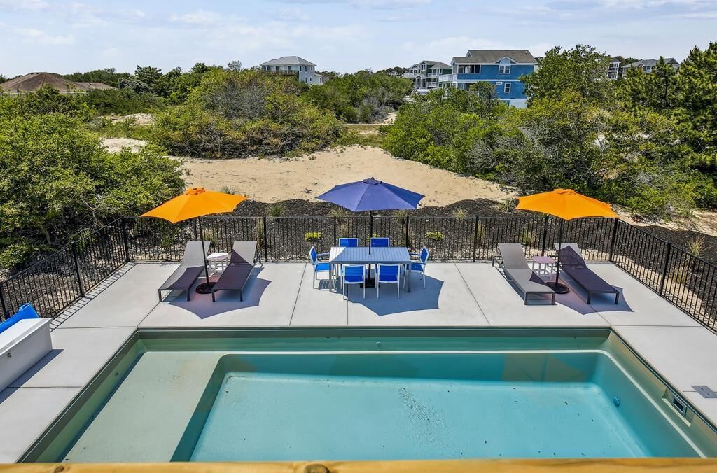 Un espace piscine comprenant un jacuzzi, des chaises longues et des parasols.