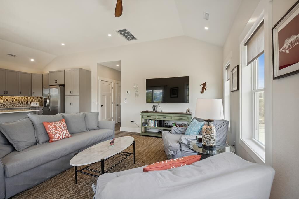 A modern living room with a grey sofa, a coffee table, and a TV mounted on the wall.