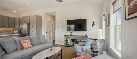 A modern living room with a grey sofa, a coffee table, and a TV mounted on the wall.