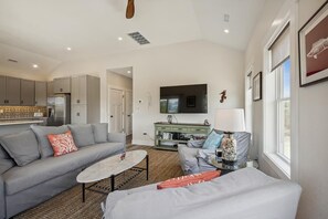A modern living room with a grey sofa, a coffee table, and a TV mounted on the wall.