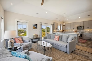 A modern living room with a sofa, coffee table, and a view of the kitchen.