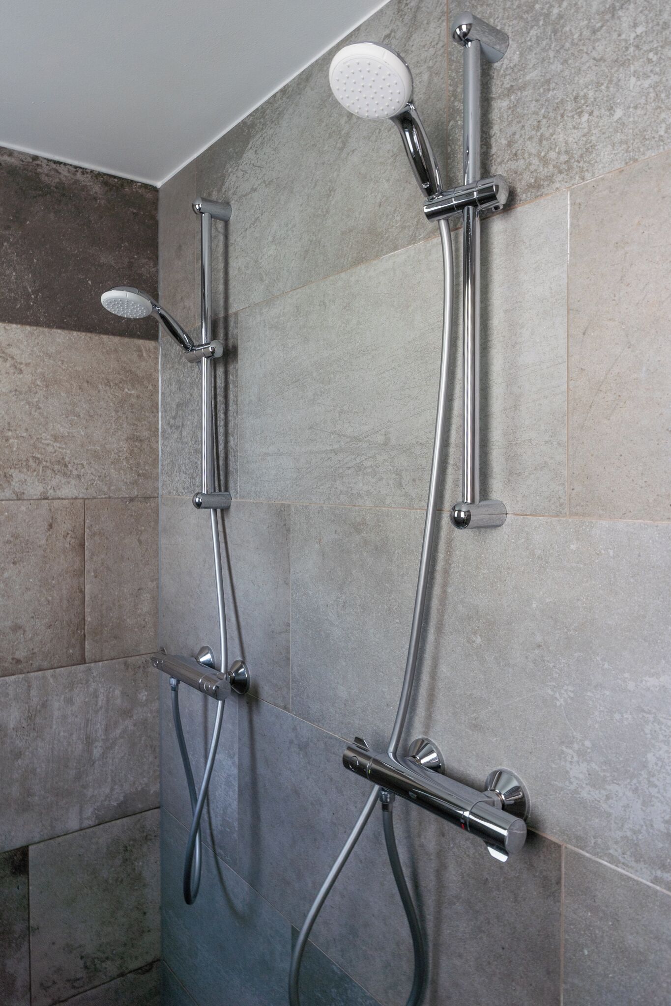 Eine Dusche mit mehreren Brauseköpfen und einer Handbrause.