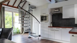 Eine moderne Küche mit eingebautem Ofen, Mikrowelle und Herd, einem Holztisch und einer Wendeltreppe, die in eine obere Ebene führt.