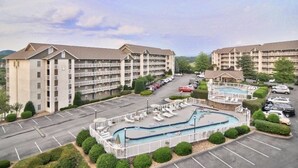 Ein Hotel mit mehreren Etagen, einem Schwimmbad und einem Parkplatz.