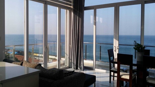 A modern living room with a large balcony overlooking the sea.