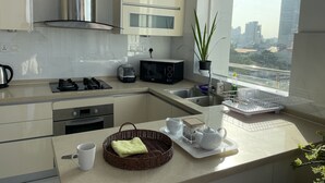 A modern kitchen with stainless steel appliances, a microwave, and a large window with a city view.