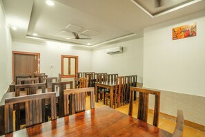 Un espace repas avec des tables et des chaises en bois, un ventilateur de plafond et un appareil de climatisation.