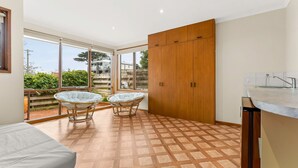 A modern kitchen with a built-in oven, a sink, and a large window. There are two wicker chairs and a wooden cabinet. - Views on Broadway - Pet friendly 4 bedroom home (San Remo)