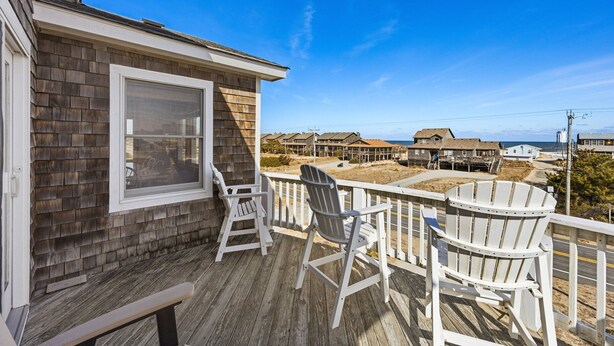 A wooden deck with white chairs and a bench, overlooking a coastal area with houses and a clear blue sky. - 6151 Once Upon a Tide * Almost Oceanfront (Nags Head)