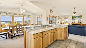 A spacious kitchen with a large island, wooden cabinets, and a view of the ocean. - 6151 Once Upon a Tide * Almost Oceanfront (Nags Head)