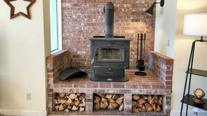 A brick fireplace with a wood stove, a star decoration, and a clock on a shelf. - Fisherman's Delight in Waldport! Dog Friendly! Hot tub! (Waldport)