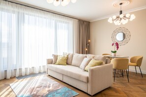 A modern living room with a beige sofa, yellow chairs, a round table, and a large window with sheer curtains. - Easyrooms Dzirnavu (Riga)
