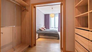 A bedroom with a bed, wooden wardrobe, and a hallway leading to another room. - Easyrooms Dzirnavu (Riga)